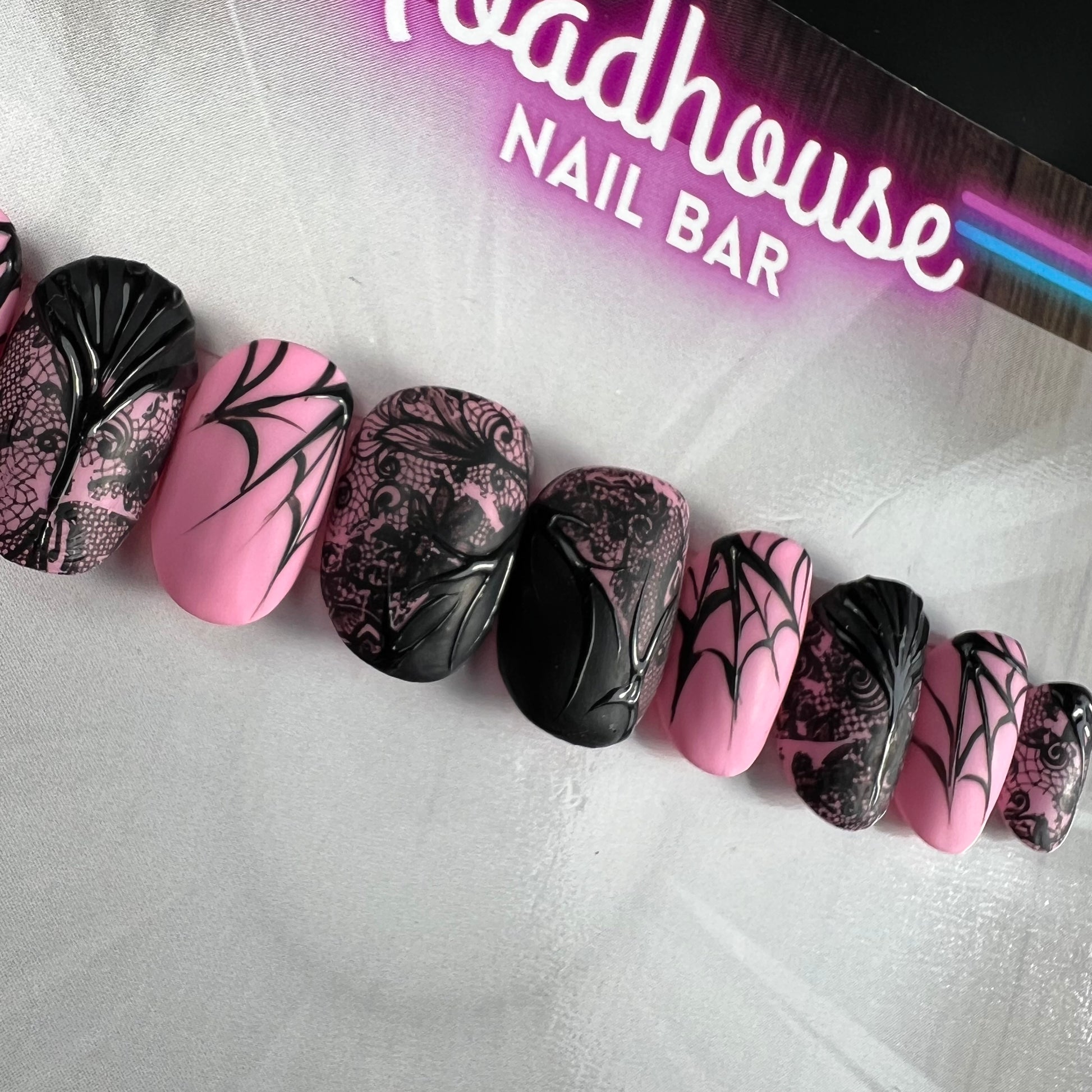 Black and pink gothic press-on nails featuring delicate spiderweb artwork and elegant alternative nail art.