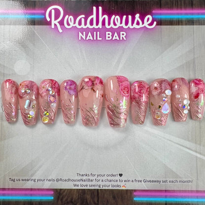 Luxury pink press-on nails featuring 3D roses, pearls and romantic textured detailing.