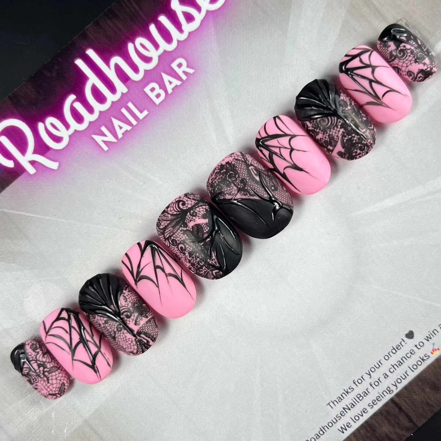 Black and pink gothic press-on nails featuring delicate spiderweb artwork and elegant alternative nail art.