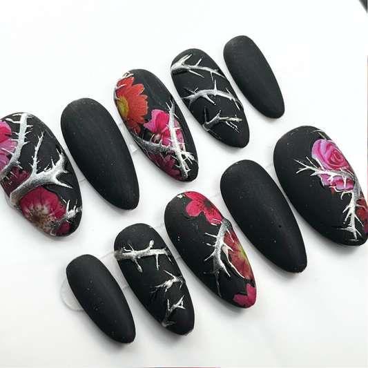 10-piece matte black press-on nail set with chrome thorn detailing and red floral accents, shown in medium almond shape for gothic summer style