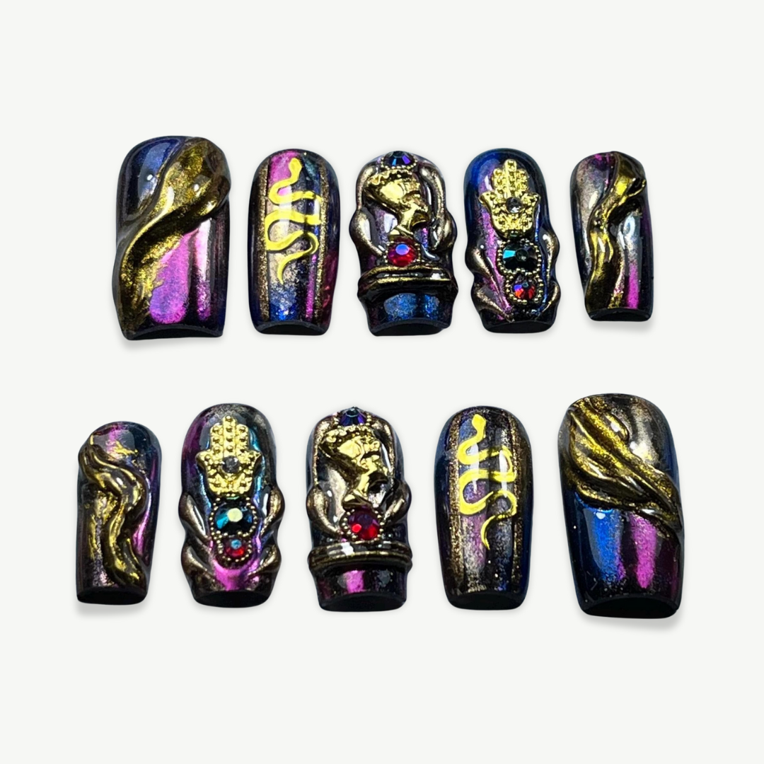 Hand-painted press-on nail set with black-purple multichrome base, featuring 3D gold Hamsa hand, snakes, and gothic baroque embellishments.

