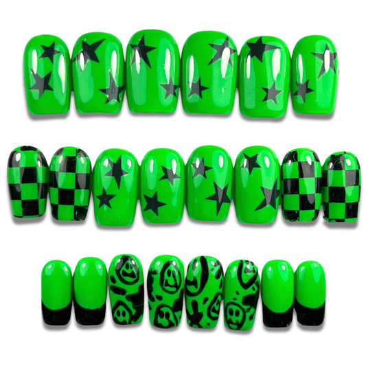 Hand with neon green and black press-on nails in short square shape featuring smiley faces, checkerboard, and punk-inspired designs – 24-piece set