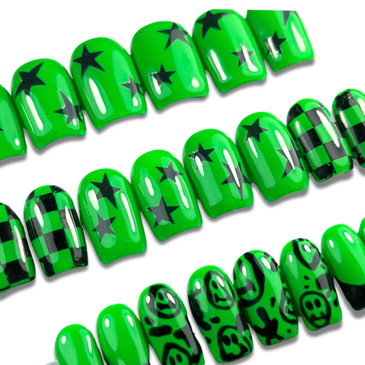 Hand with neon green and black press-on nails in short square shape featuring smiley faces, checkerboard, and punk-inspired designs – 24-piece set